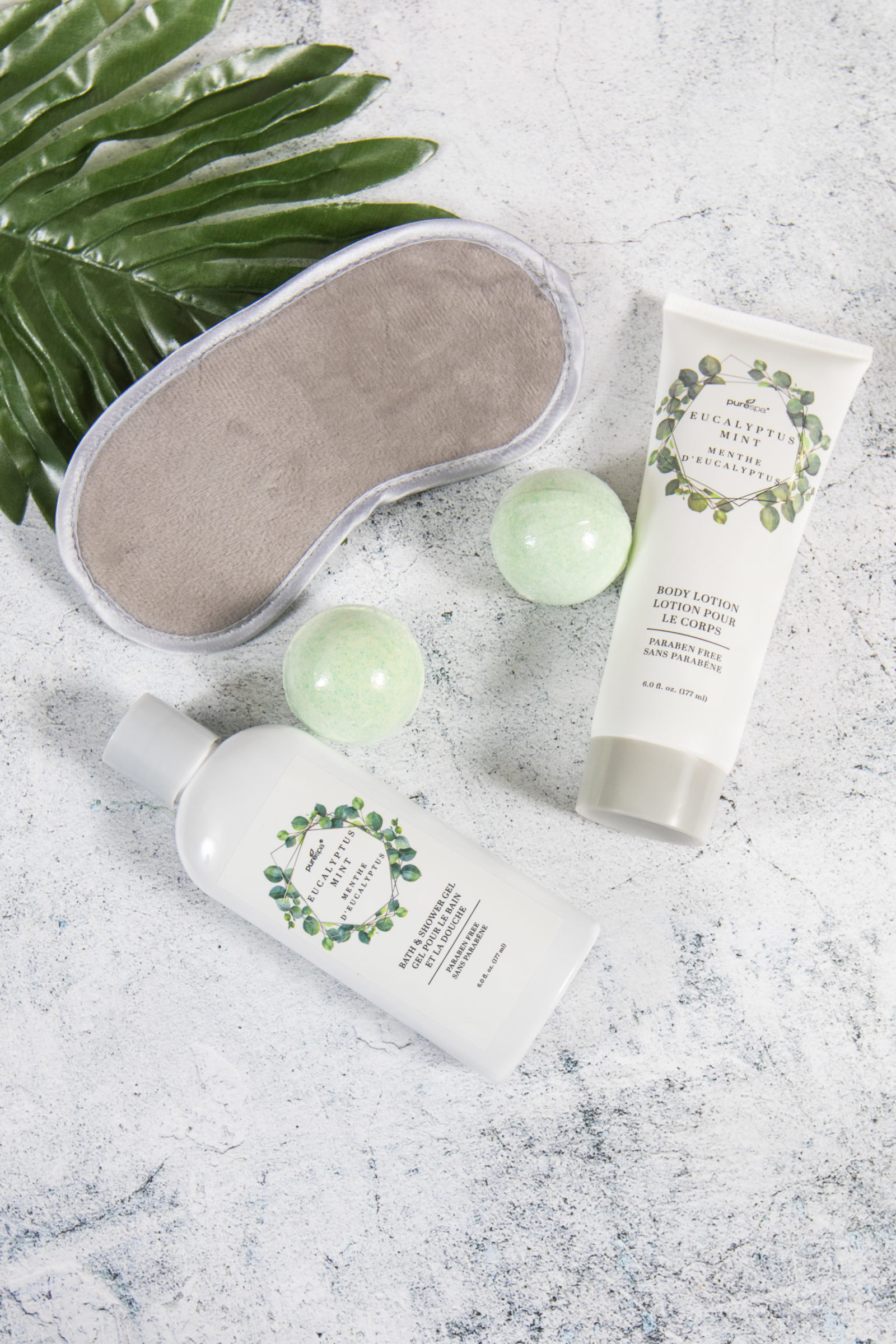 shower gel, body lotion, bath bombs and sleep mask arranged together to show off the products for a spa gift set.